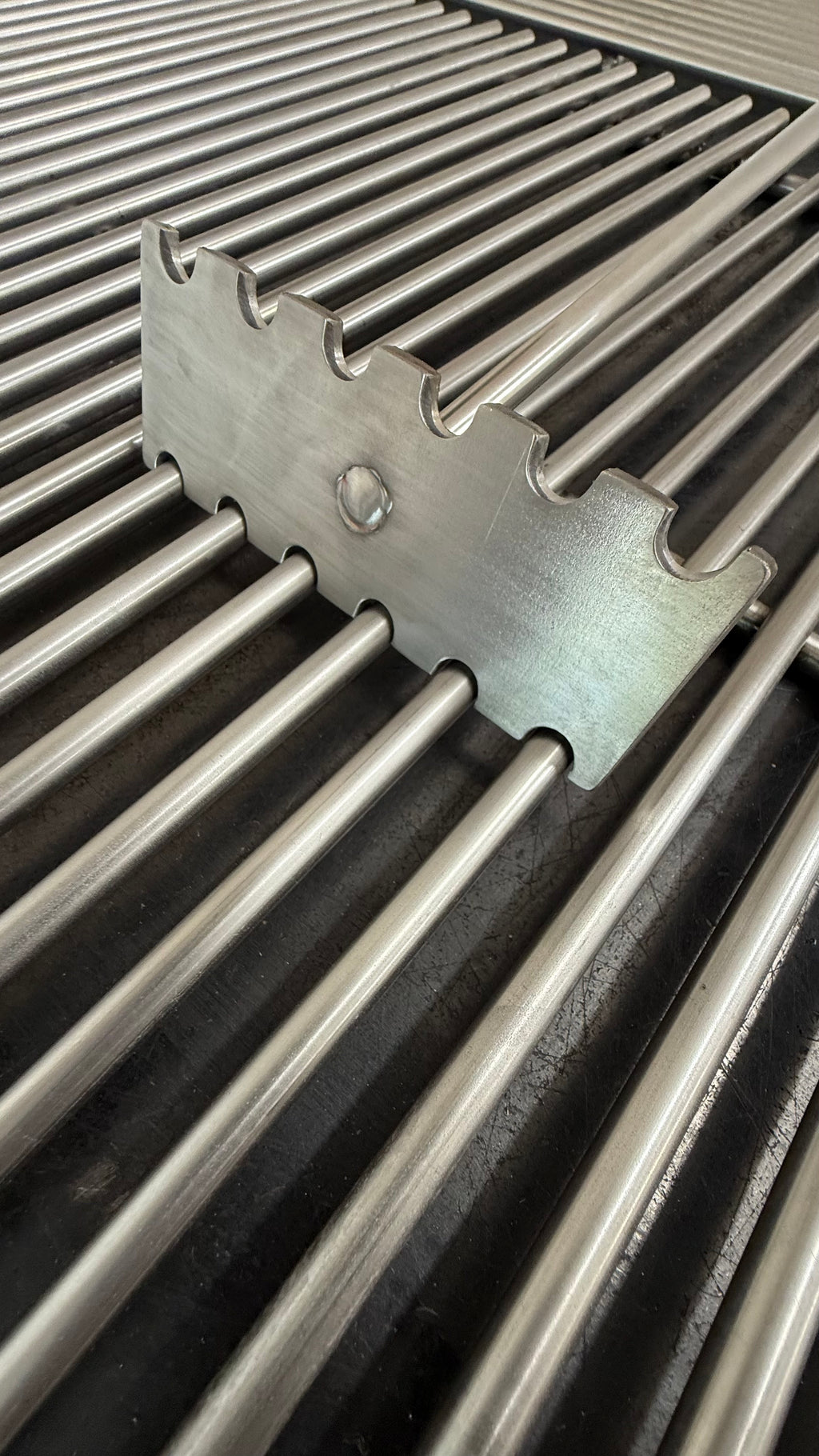 Stainless steel grate cleaner scraping a 3/8-inch round bar grill grate